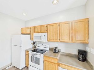 Apartments for rent in Limerick PA USA A small kitchen with light wood cabinets, white appliances including a fridge, stove, and microwave, and a countertop with a toaster and coffee maker.