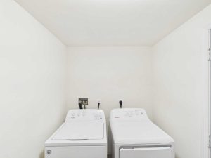 Apartments for rent in Limerick PA USA A white laundry room with a top-loading washing machine on the left and a front-loading dryer on the right, both against a plain wall.