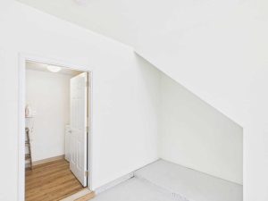 Apartments for rent in Limerick PA USA A small empty space under a staircase next to a white door that opens into a room with wood flooring and visible shelves.