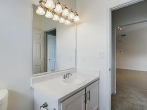 A bathroom with a sink, toilet and mirror designed for media purposes.