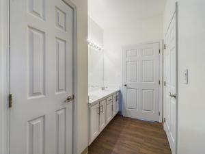 A media hallway with white doors and wood floors.