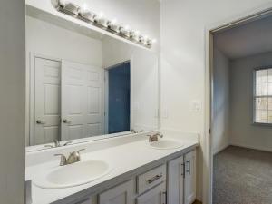 A modern bathroom with two sleek sinks, a large mirror, and media capabilities.