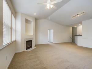 An empty living room with a fireplace and a media console.