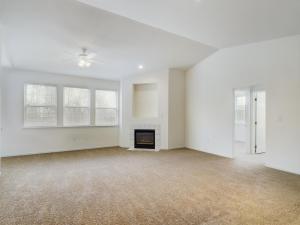     Description: Empty living room with beige carpet and a media fireplace.