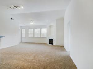 Empty living room with beige carpet, ceiling fan, and media.